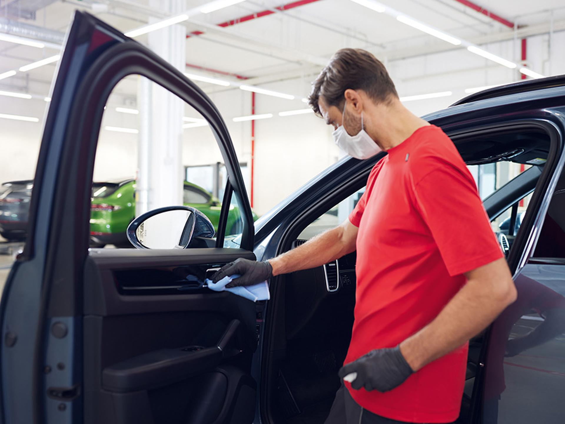Ein Techniker pflegt und reinigt die Autotür eines Macans.