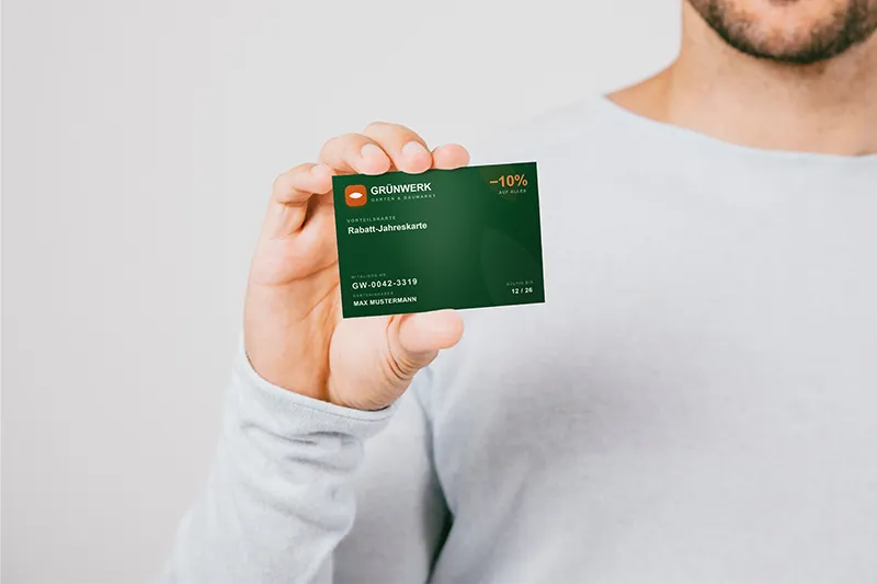 Ein Mann hält eine sogenannte Membership-Card frontal in die Kamera, darauf ist ein 10% Rabatt der Grünwerk zu sehen.