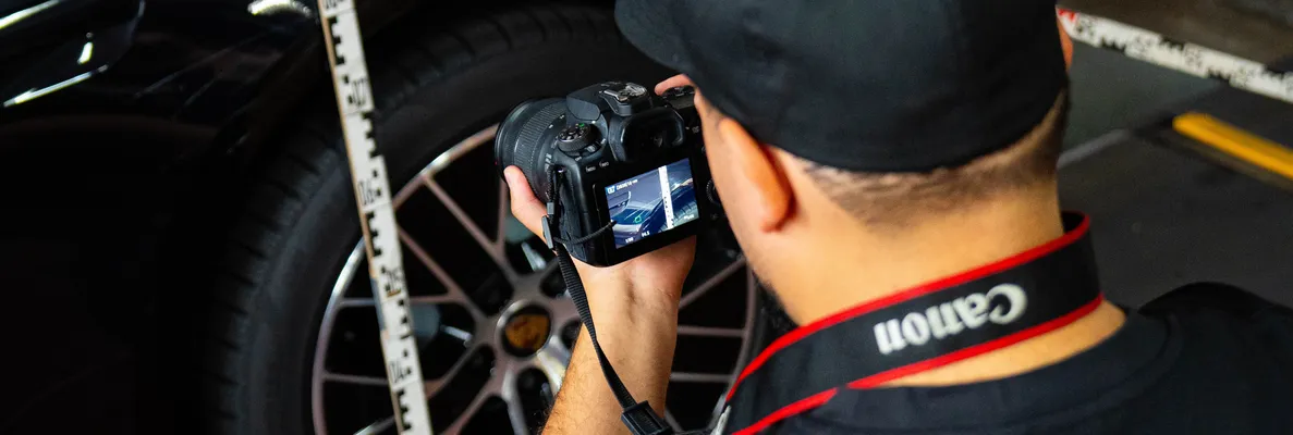 Gutachter fotografiert den Radkasten eines schwarzen Autos mit angelegtem Zollstock
