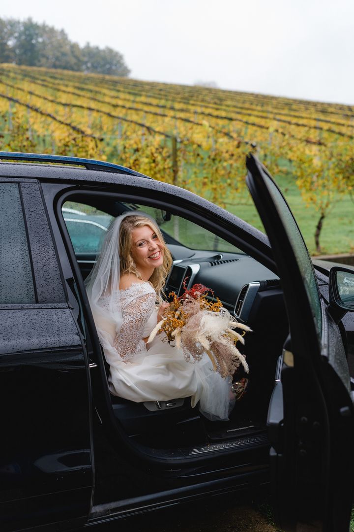 Braut lächelt im Auto beim Weinberg