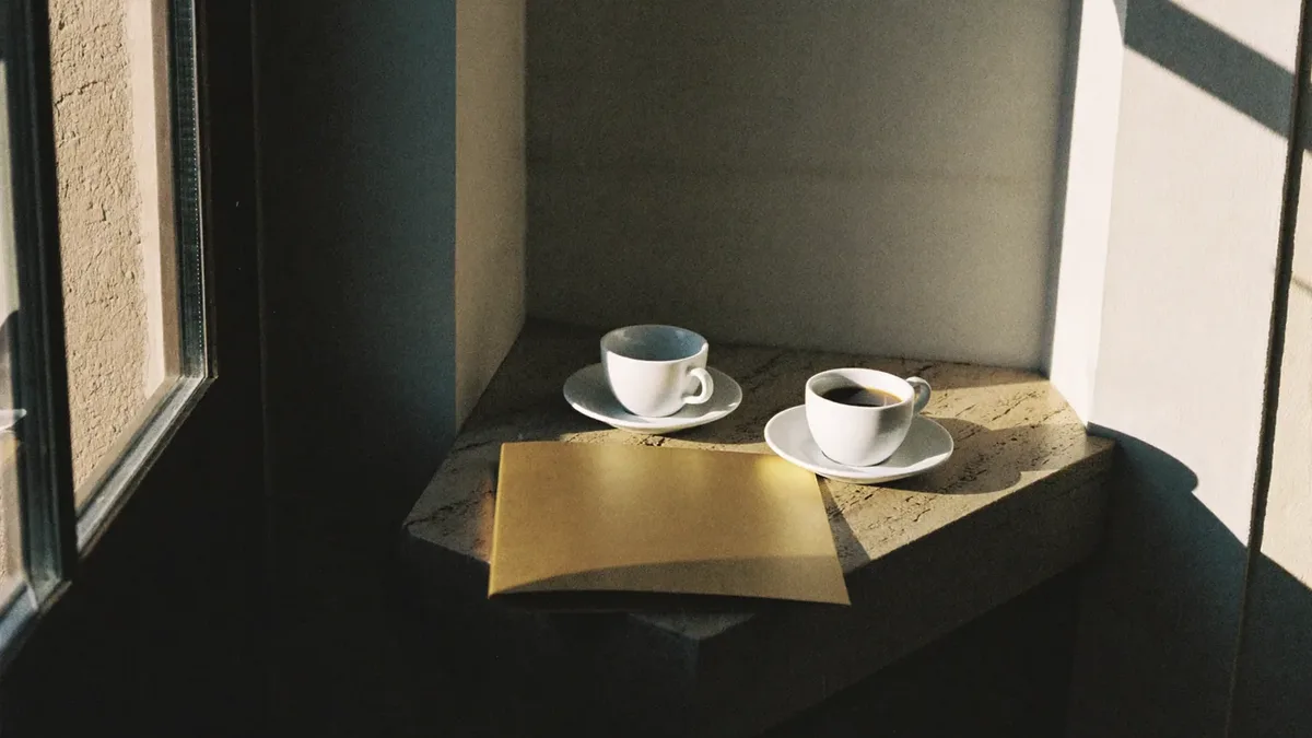 Coffee cups and a folder on a stone ledge by a window