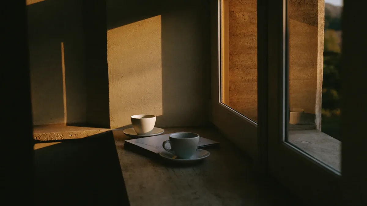 Coffee cups and a folder on a stone ledge by a window