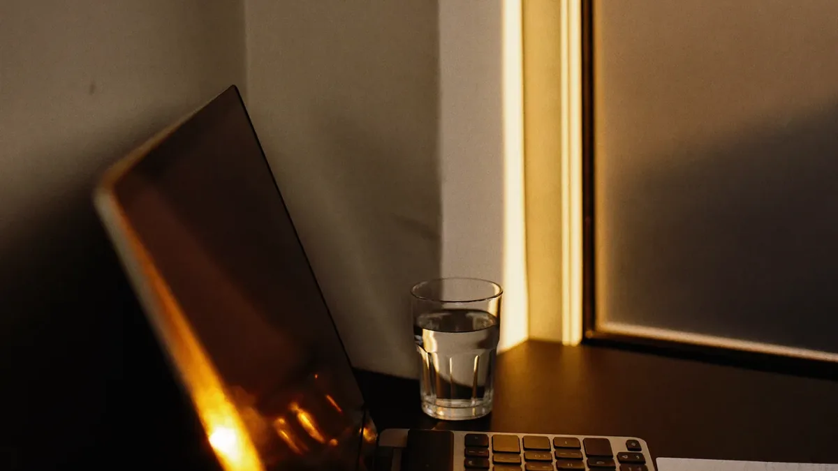 Desk corner lit by the glow of a screen at dusk