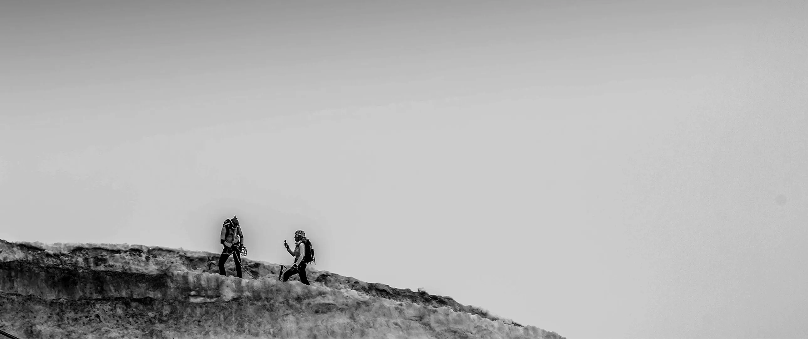 Two Venari Partners Challenge trekkers crossing a mountain ridge under an open sky