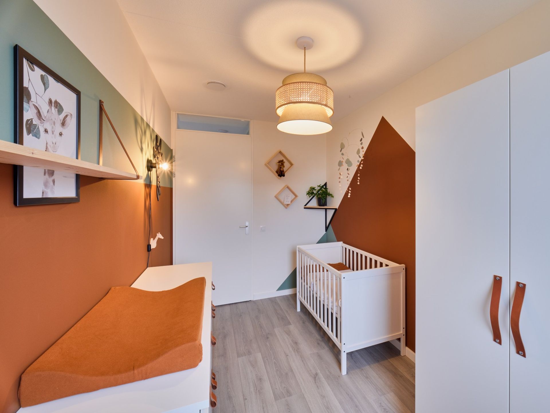 Overzicht van babykamer Quinn met bestaande kast, wit ledikant, commode en rustige geometrische wandvlakken.
