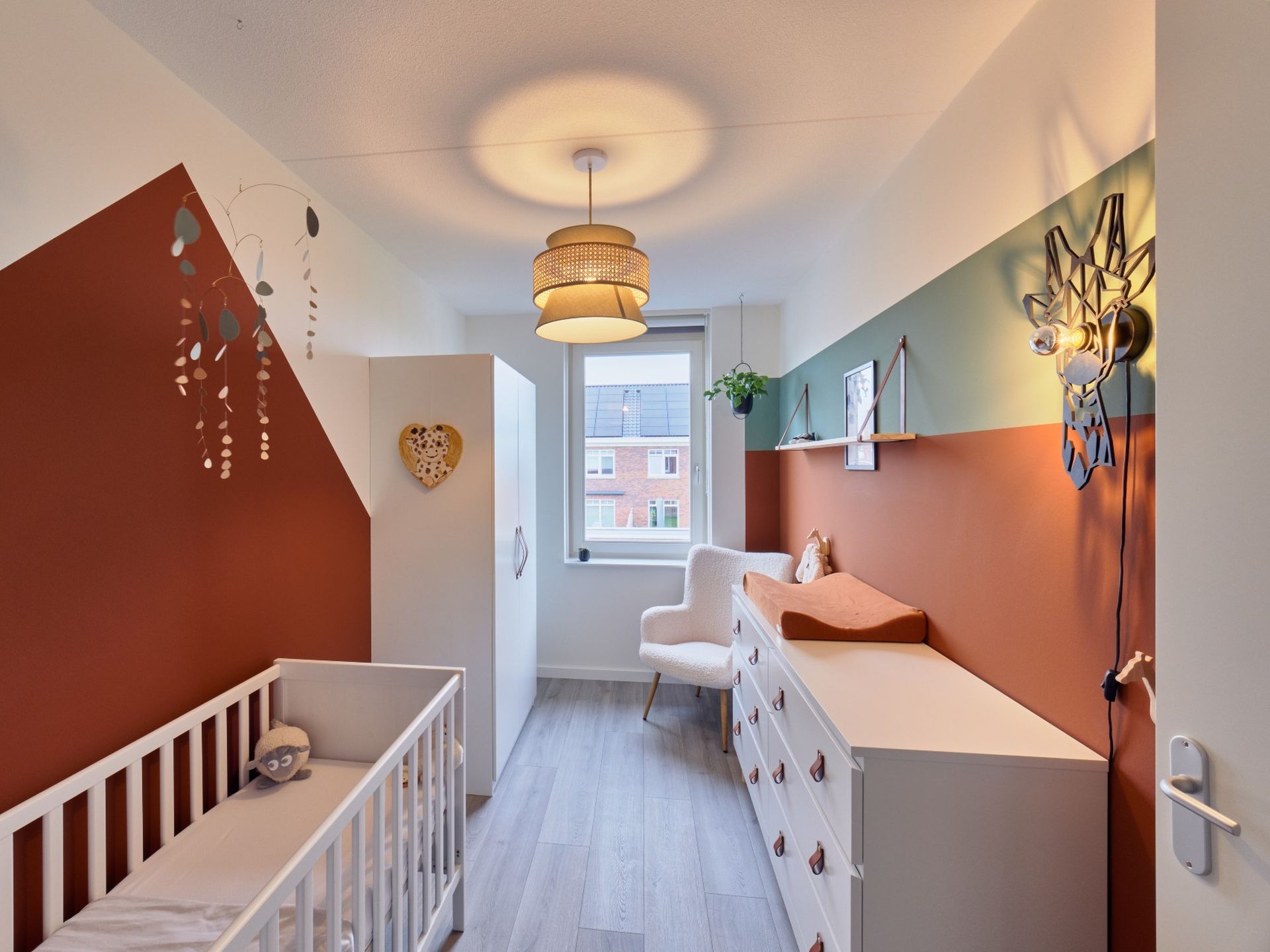 Gerealiseerde babykamer in Zuidland met ledikant, commode, geometrische kleurvlakken en giraffelamp in een ontwerp van STOERR.
