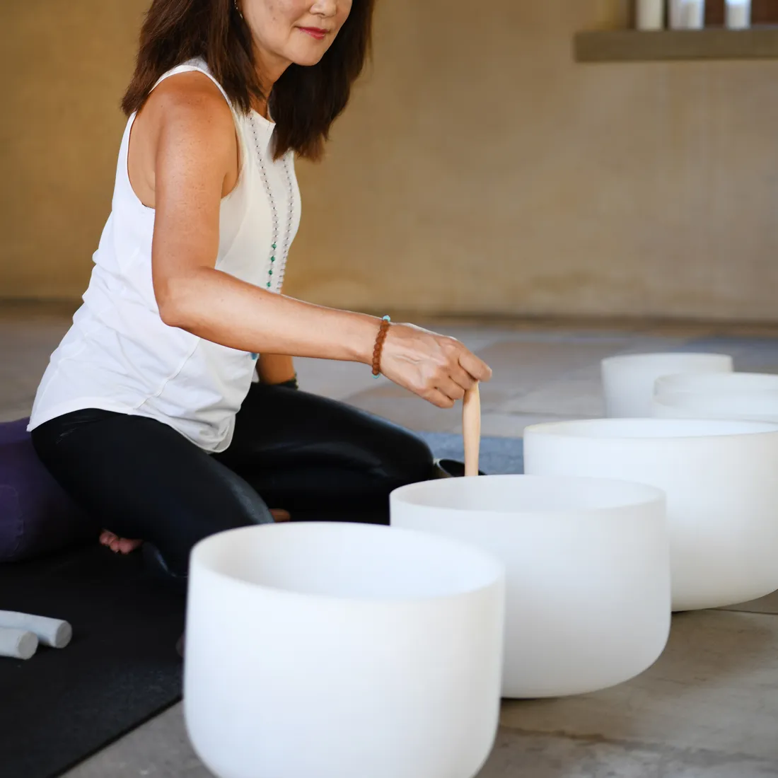 a woman sitting on the floor playing with white bowls