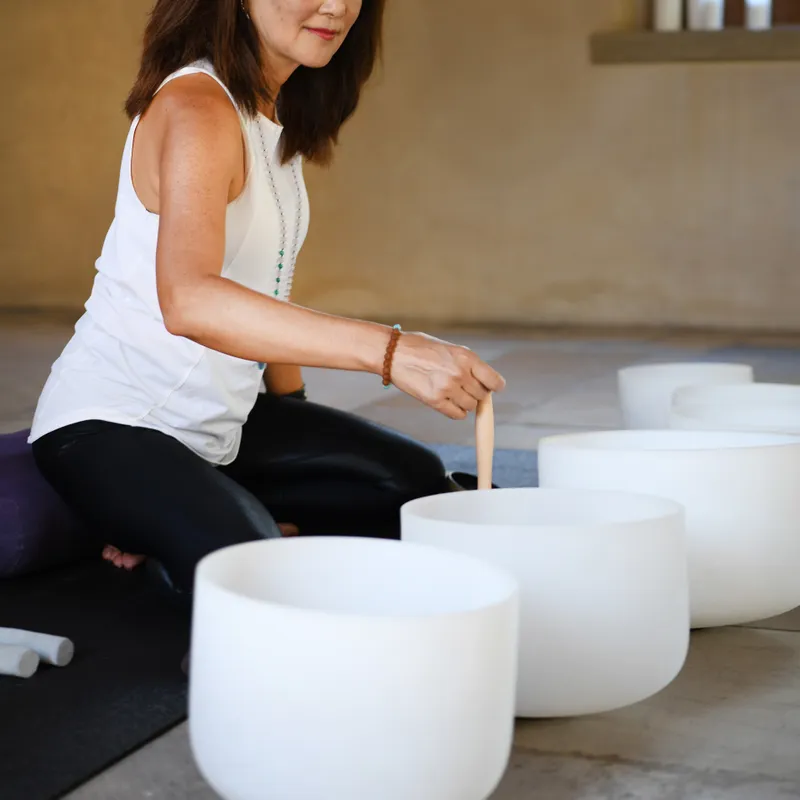 a woman sitting on the floor playing with white bowls