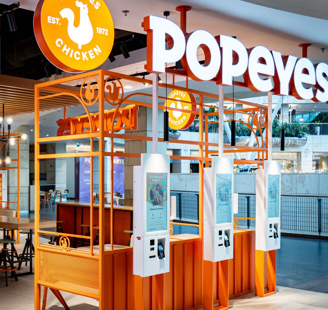 Guests ordering at self-service kiosks in a Popeyes restaurant