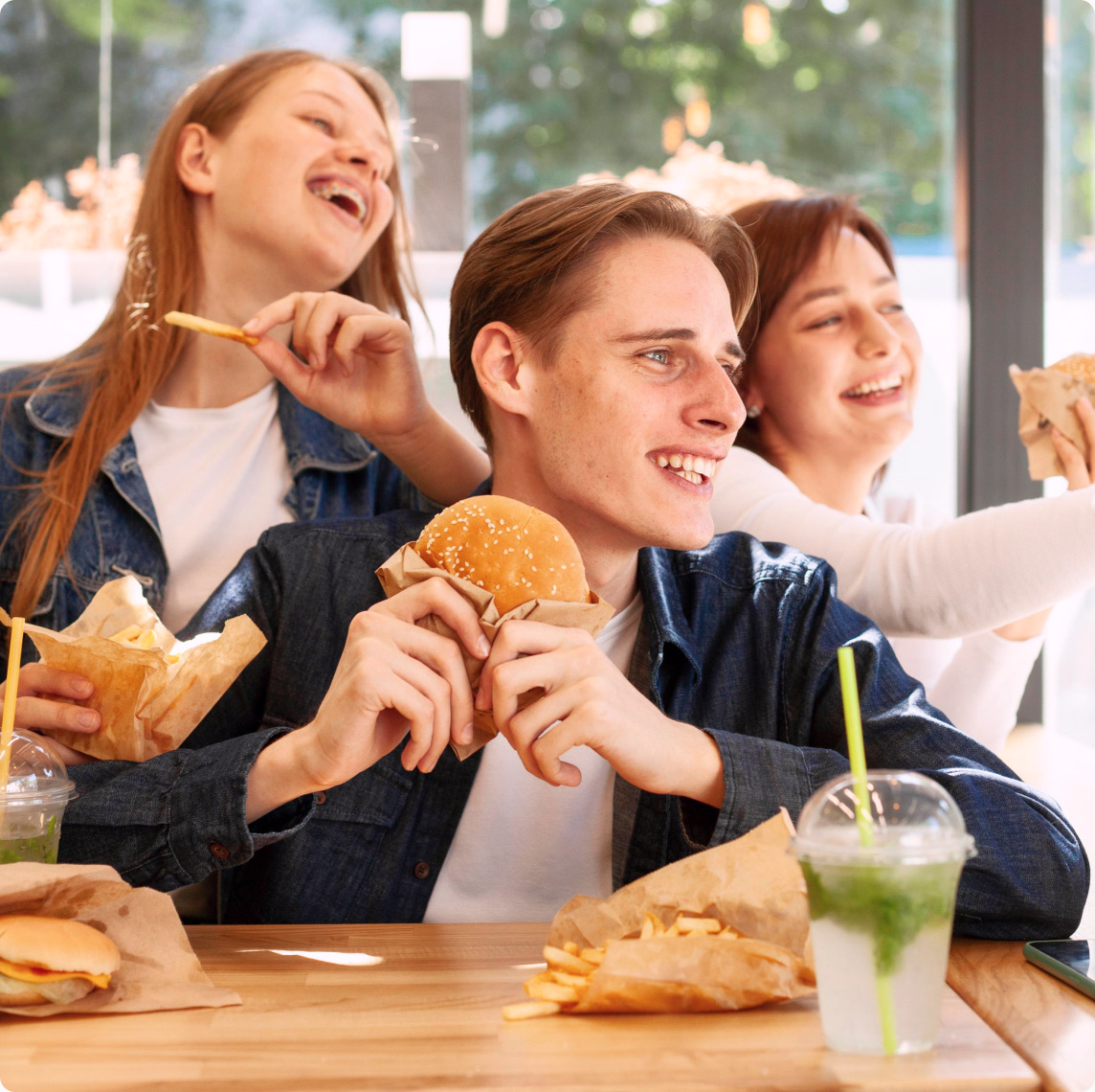 Friends laughing while sharing burgers and fries