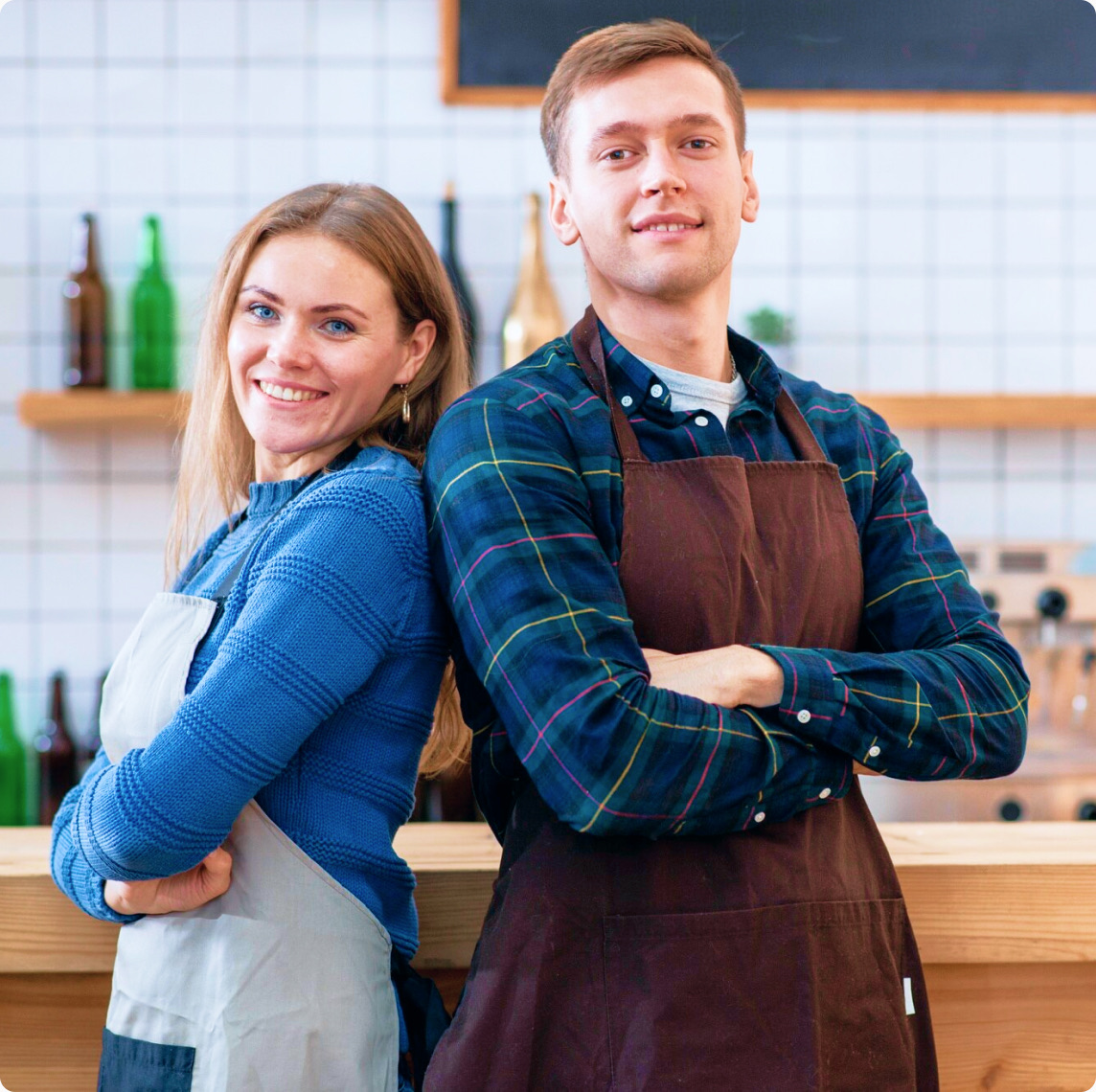Two restaurant owners in aprons standing back to back at the counter