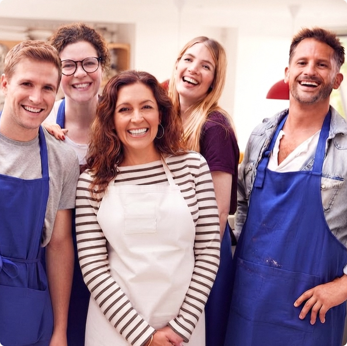 Smiling restaurant kitchen team in aprons