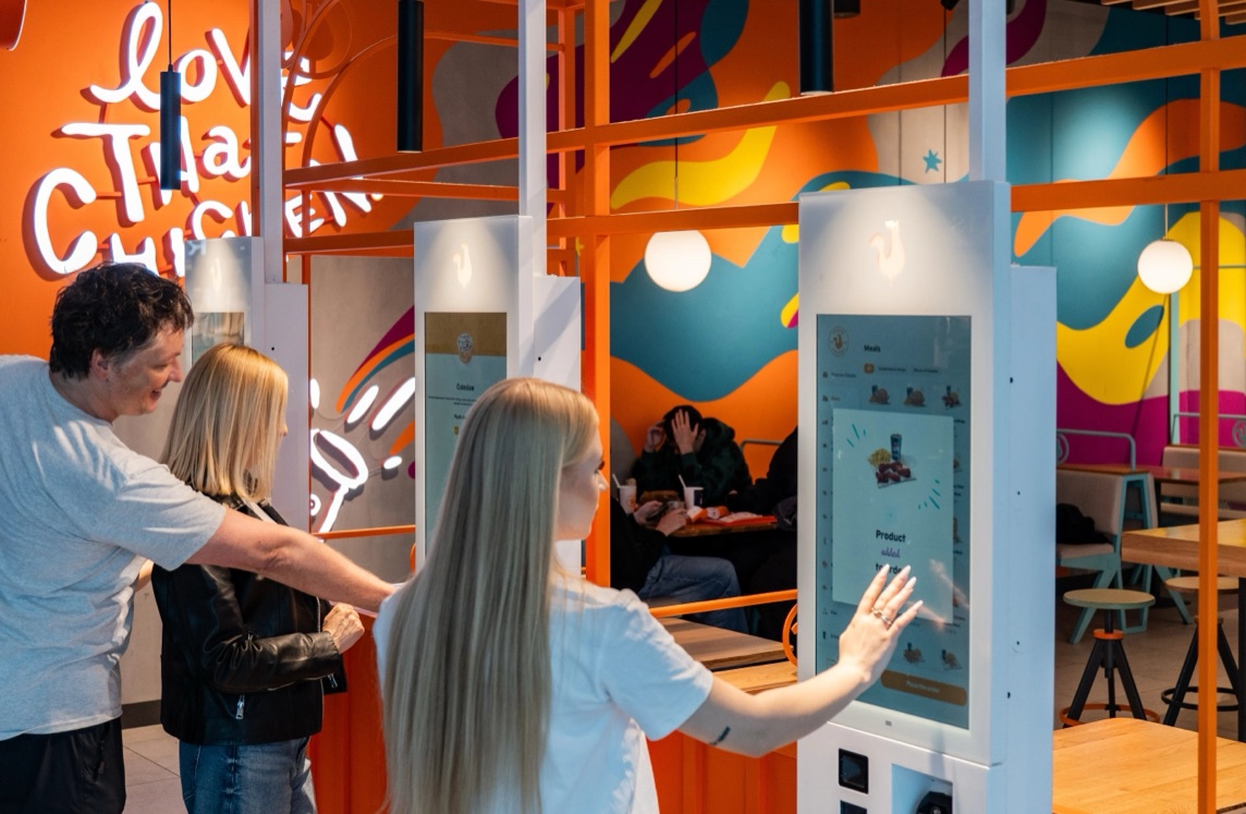 Guests ordering at self-service kiosks in a Popeyes restaurant