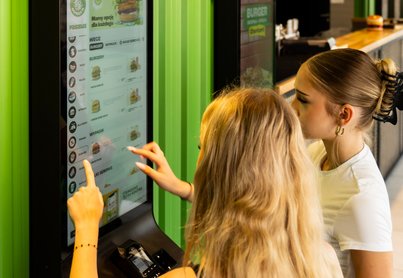 Two guests browsing the menu on a self-service ordering kiosk
