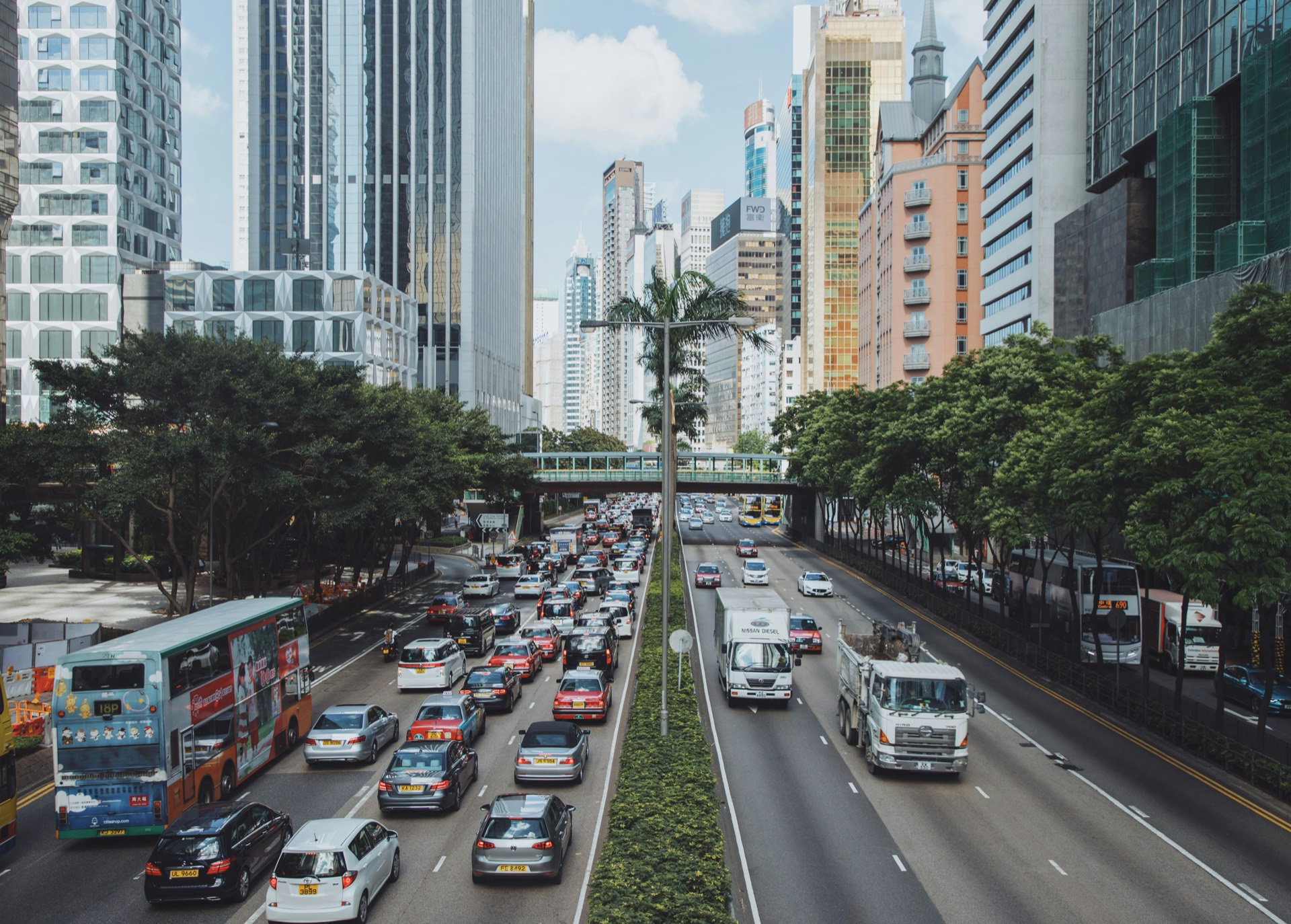 A busy multi-lane city avenue with dense traffic between high-rise towers.