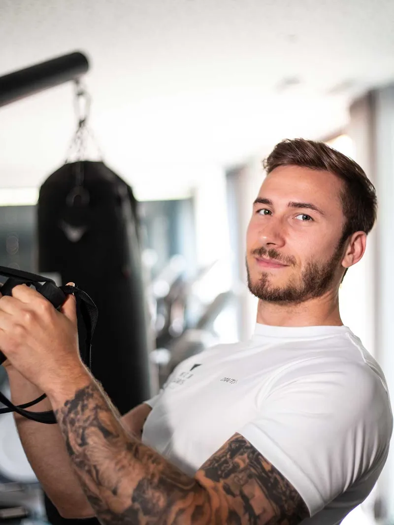 Mann trainiert mit Klettergurt im Fitnessraum