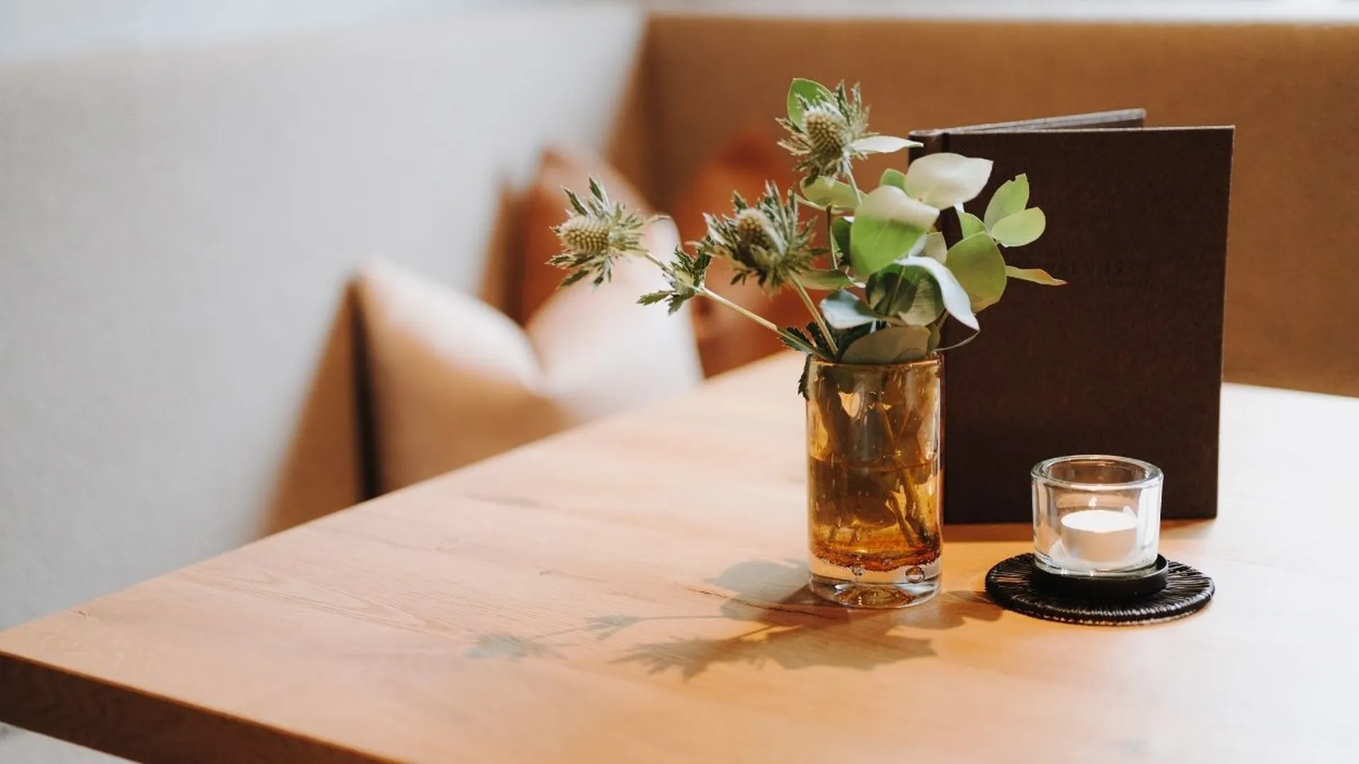 Tisch mit Blumenvase, Teelicht und Speisekarte im Restaurant