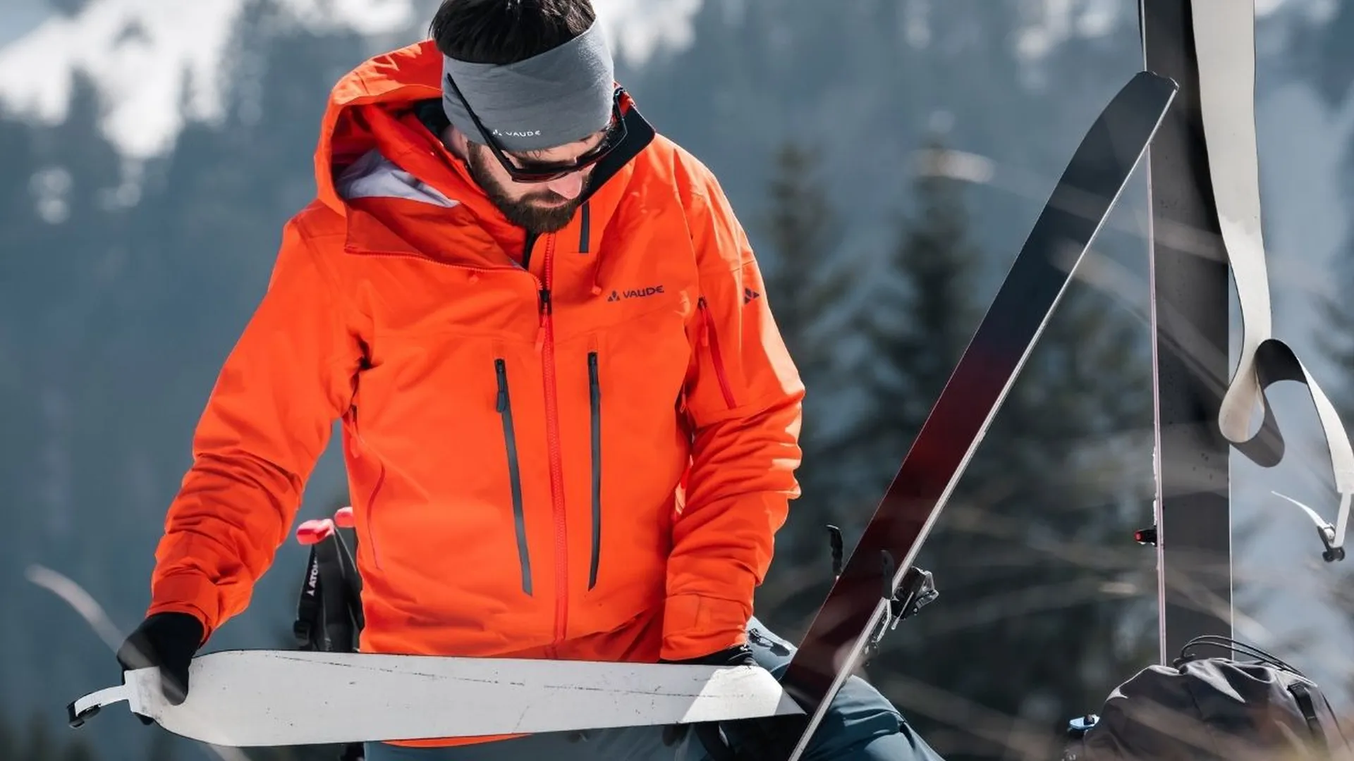Skitourengeher präpariert Skifelle in verschneiter Berglandschaft