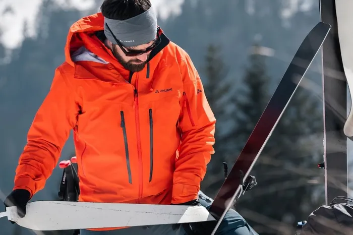 Skitourengeher präpariert Skifelle in verschneiter Berglandschaft
