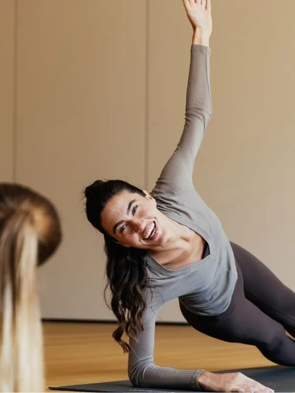 Zwei Frauen machen Yoga in Seitenstütz-Position im Kursraum