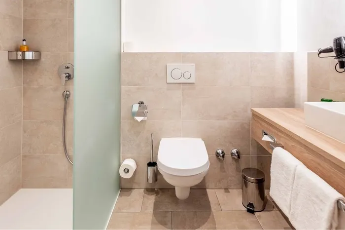 Modernes Hotelbadezimmer mit Dusche, WC und Waschtisch aus Holz