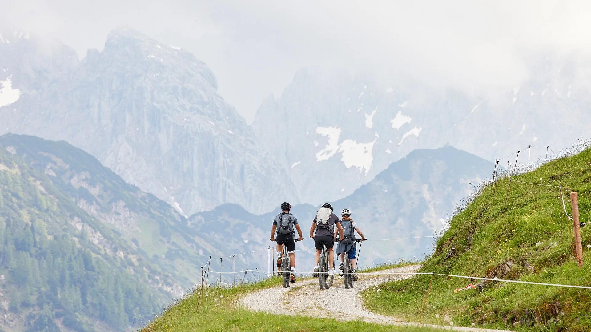 Mountainbiker auf Schotterweg vor Bergpanorama
