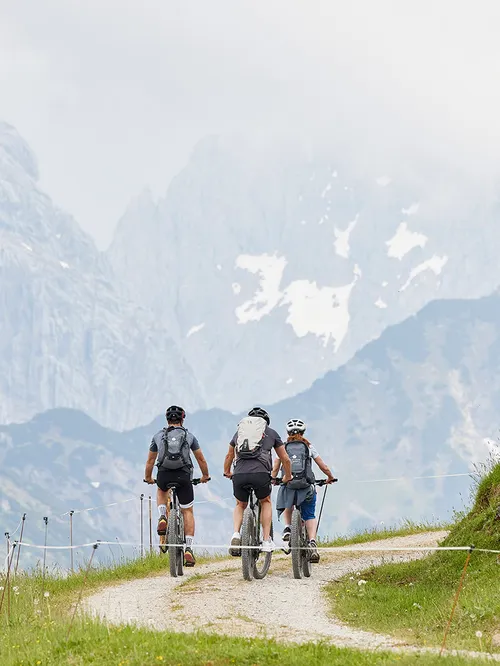Mountainbiker auf Schotterweg vor Bergpanorama