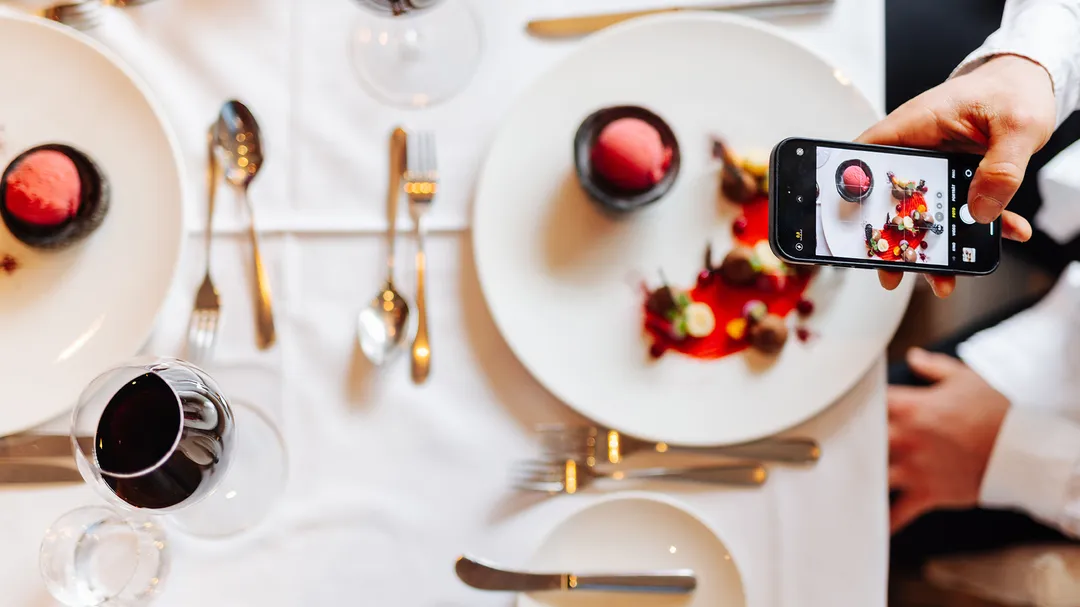 Smartphone-Foto eines Desserttellers auf gedecktem Restauranttisch