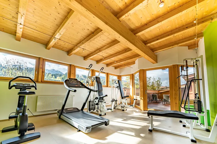 Fitnessraum mit Holzdachkonstruktion, Laufband und Trainingsgeräten mit Bergblick
