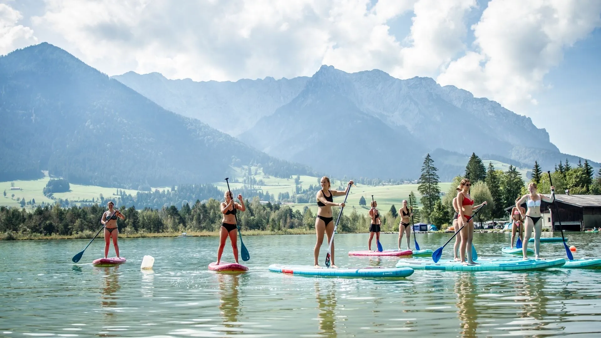Gruppe beim Stand-Up-Paddling auf einem Bergsee vor Alpenkulisse