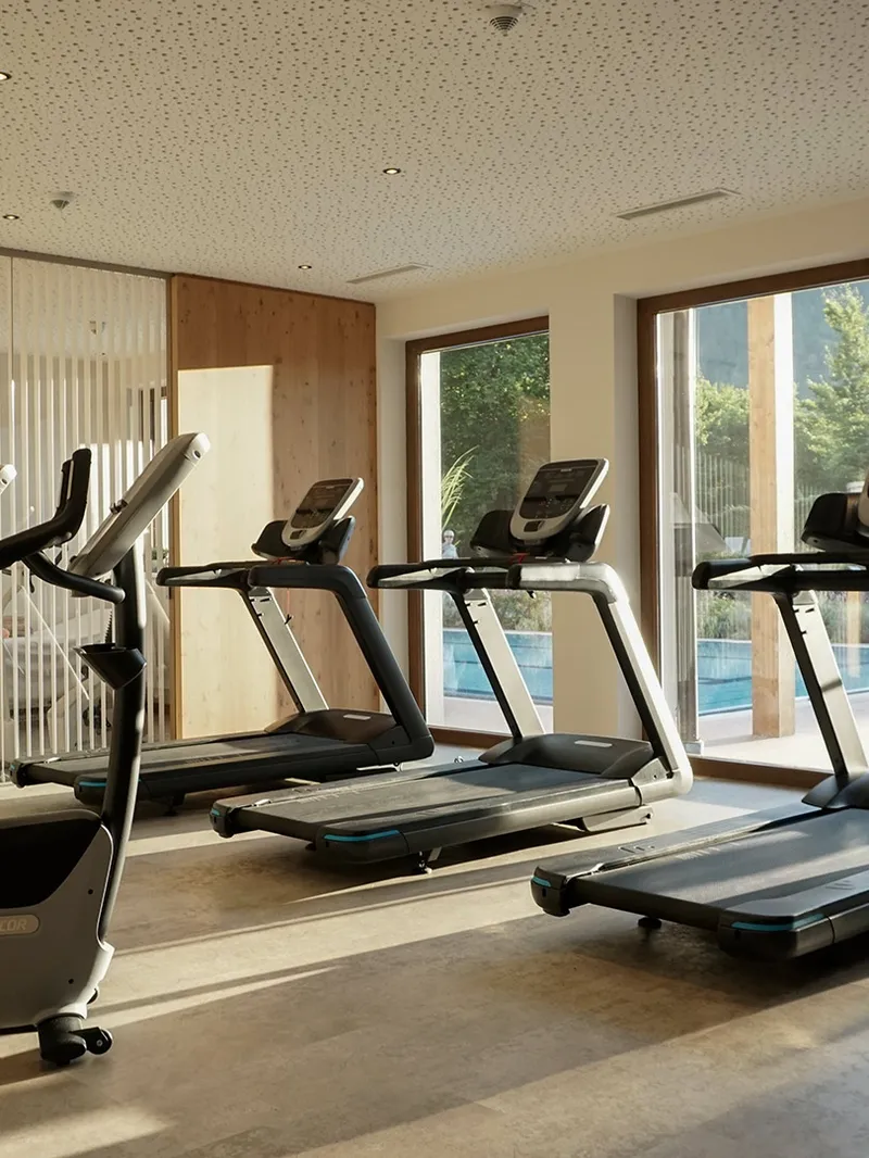 Fitnessraum mit Laufbändern und Fahrrädern, Blick auf Pool und Berge