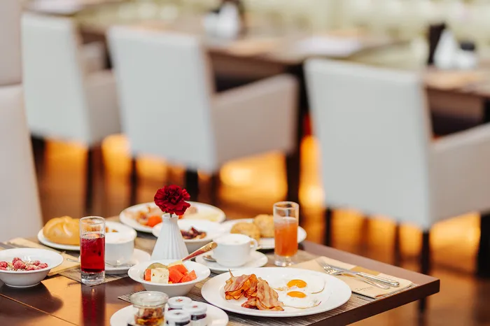 Gedeckter Frühstückstisch mit Spiegeleiern, Speck, Obst und Getränken im Restaurant