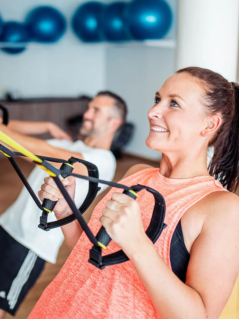 Personen beim TRX-Training im Fitnessraum