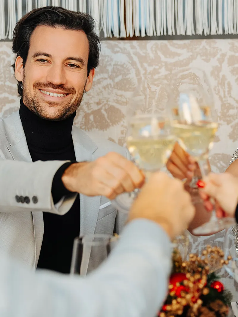 Festlich gekleidete Gäste stoßen beim Dinner mit Sektgläsern an