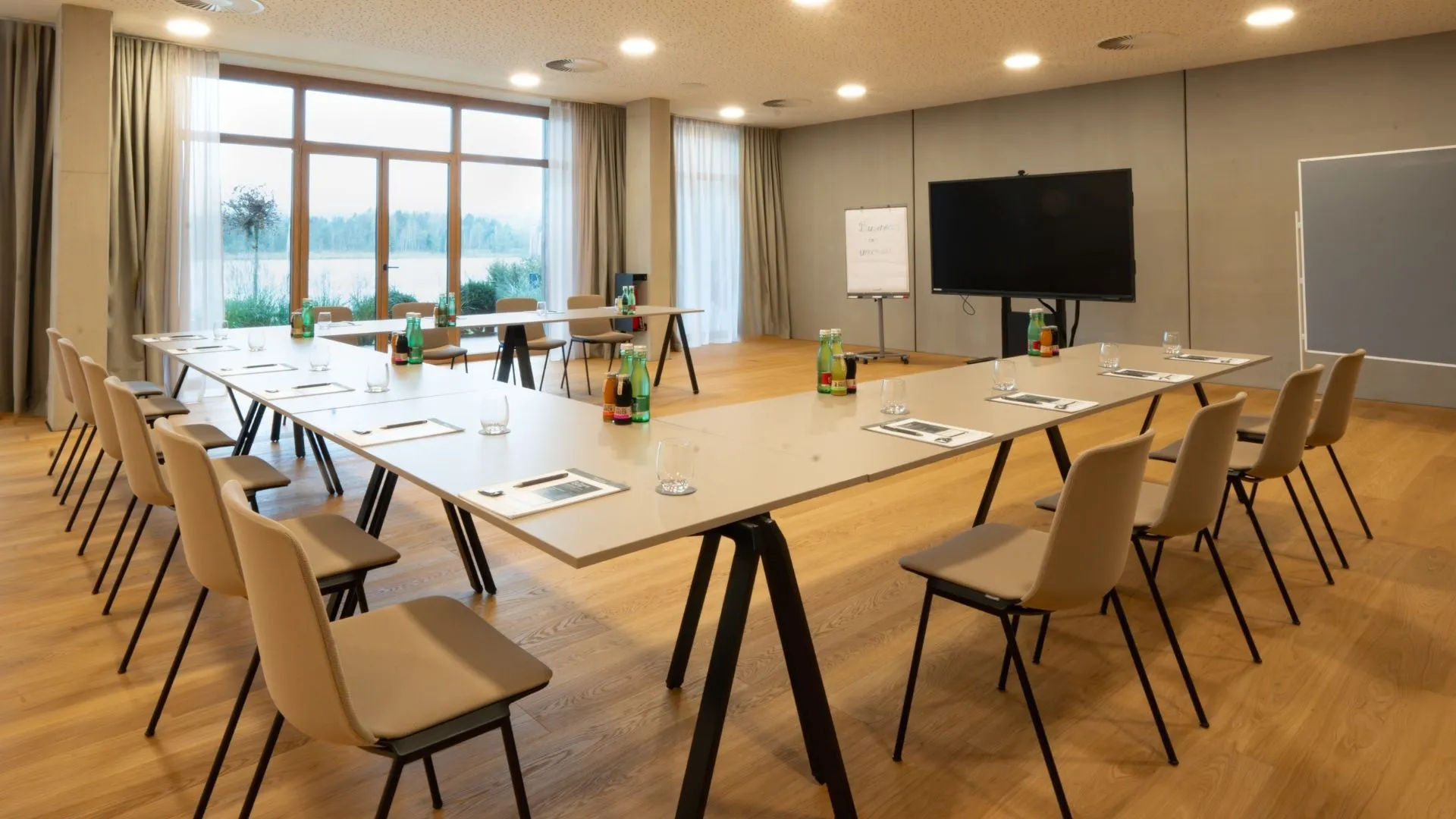 Seminarraum mit U-förmiger Tischanordnung, Bildschirm und Seeblick