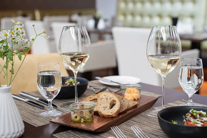 Gedeckter Restauranttisch mit Weißwein, Wasser, Brot und Vorspeisen