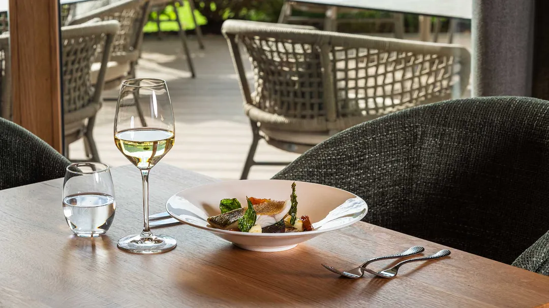 Gedeckter Tisch mit Fischgericht und Weißwein auf der Restaurantterrasse