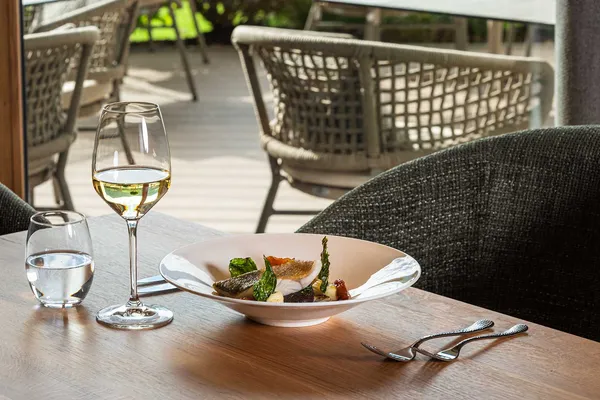 Gedeckter Tisch mit Fischgericht und Weißwein auf der Restaurantterrasse