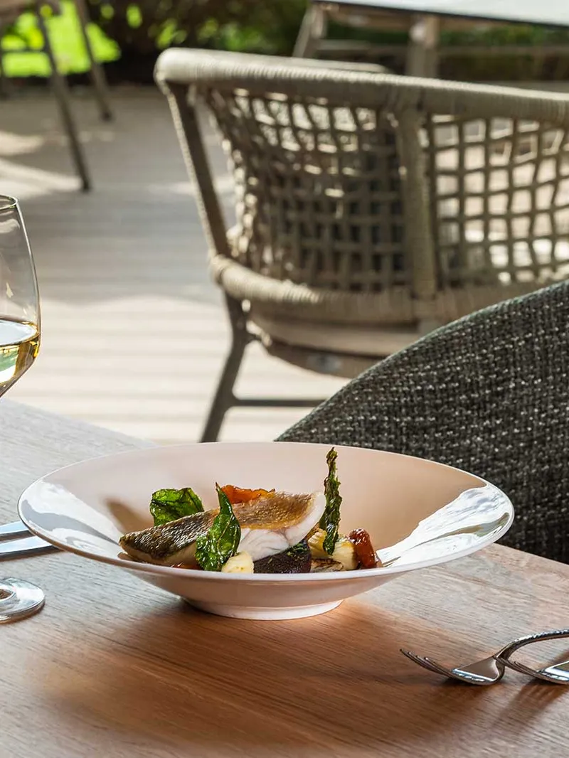 Gedeckter Tisch mit Fischgericht und Weißwein auf der Restaurantterrasse