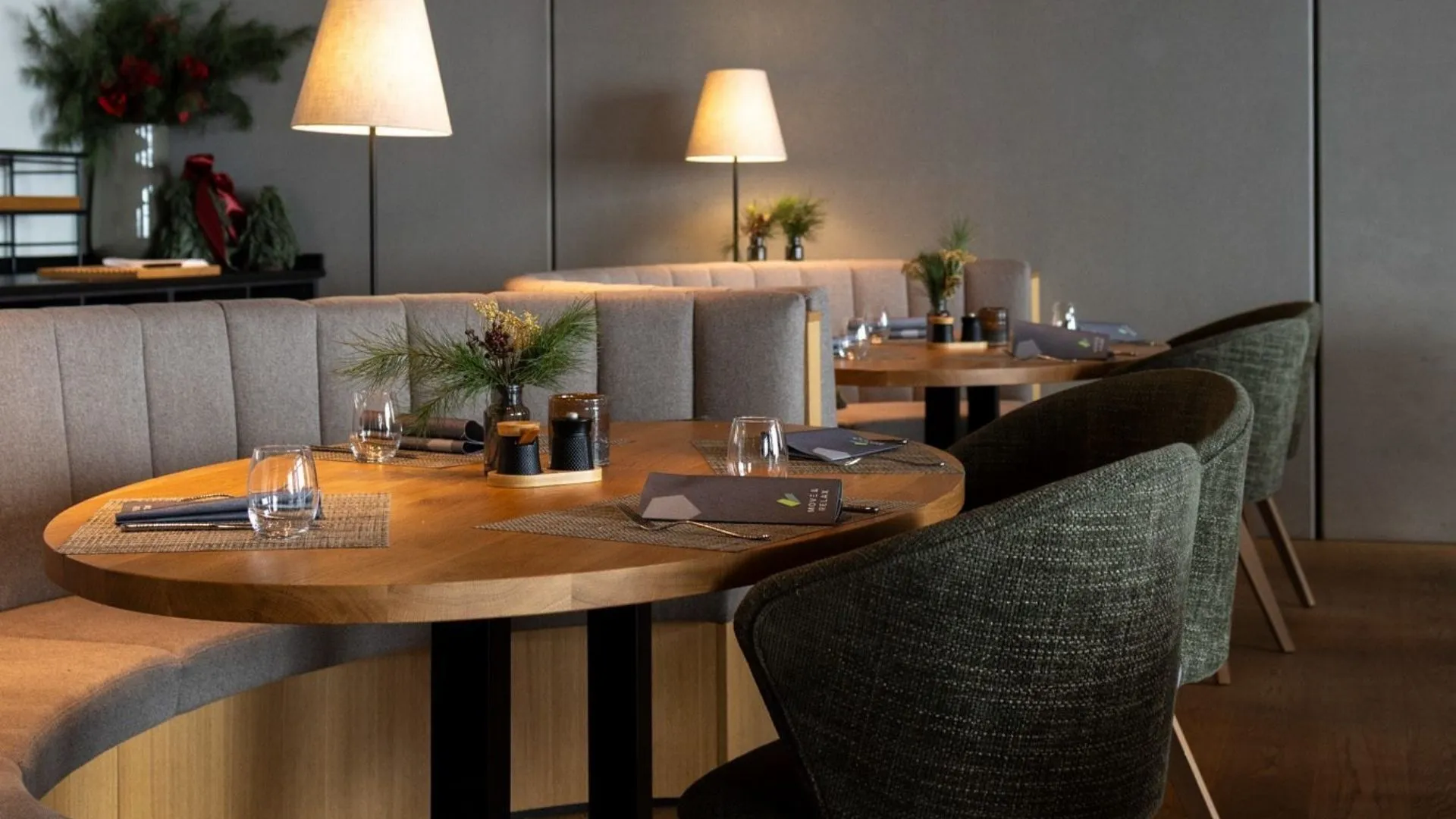 Gedeckte Tische mit Polsterbänken und Sesseln im Restaurant