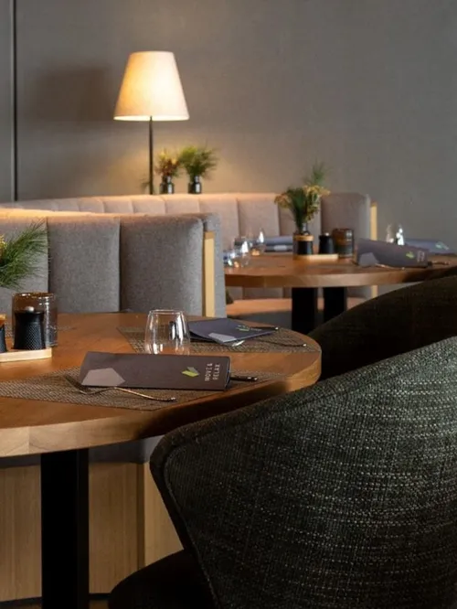 Gedeckte Tische mit Polsterbänken und Sesseln im Restaurant