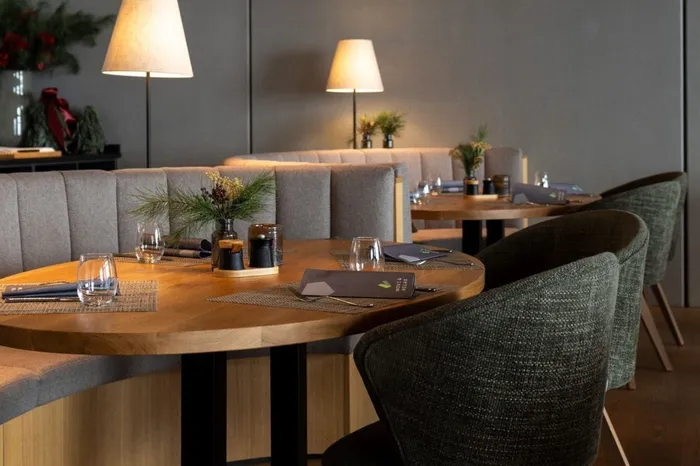 Gedeckte Tische mit Polsterbänken und Sesseln im Restaurant