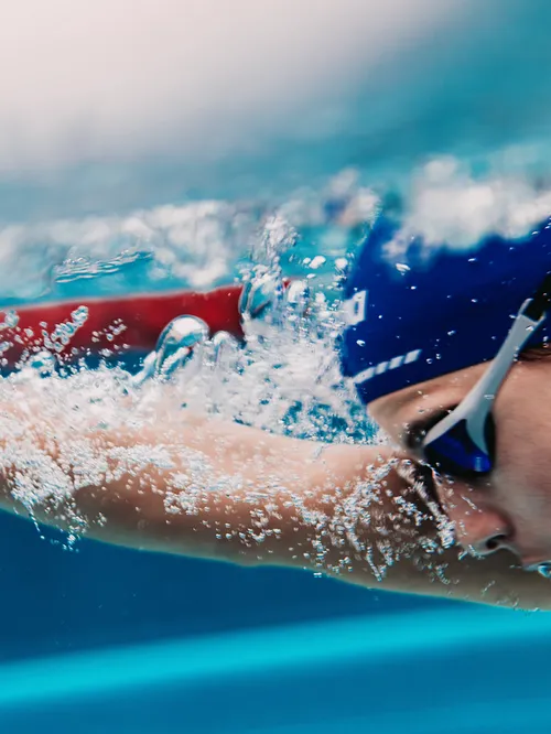 Schwimmer mit Badekappe und Schwimmbrille beim Kraulen im Pool