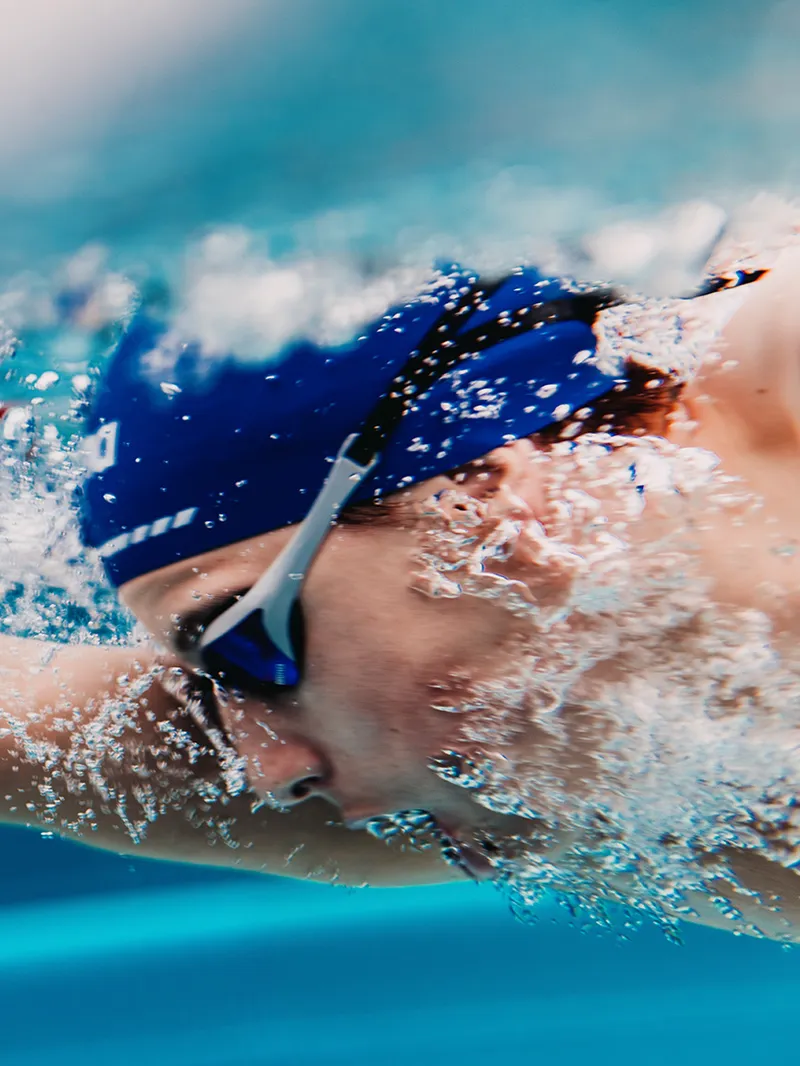 Schwimmer mit Badekappe und Schwimmbrille beim Kraulen im Pool