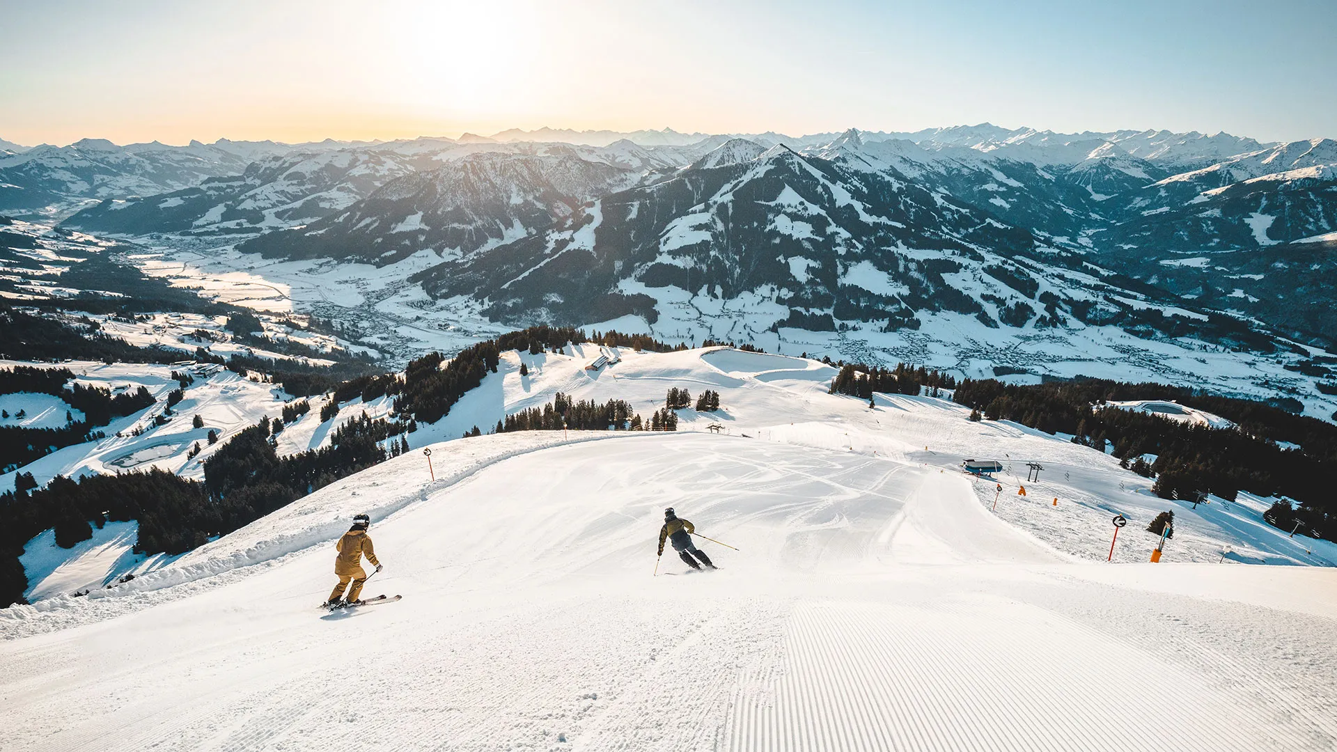 Skifahrer auf präparierter Piste mit Panoramablick auf verschneite Bergkette