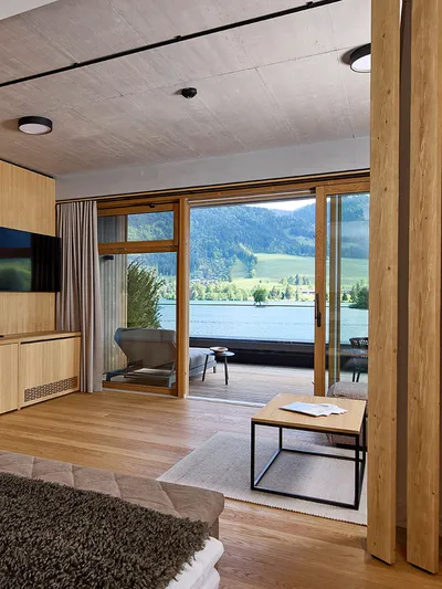 Hotelzimmer mit Holzeinrichtung, Sitzecke und Seeblick