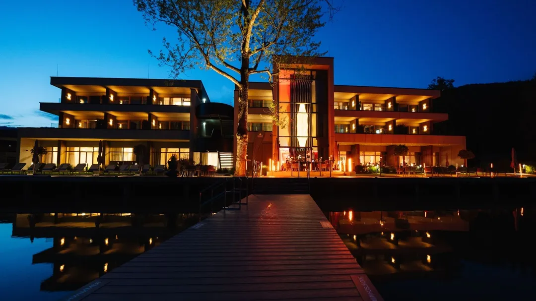 Hotel am See beleuchtet in der Abenddämmerung mit Steg