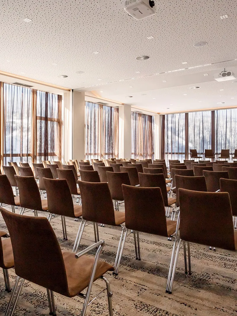 Seminarraum mit Stuhlreihen und großen Fenstern mit Bergblick