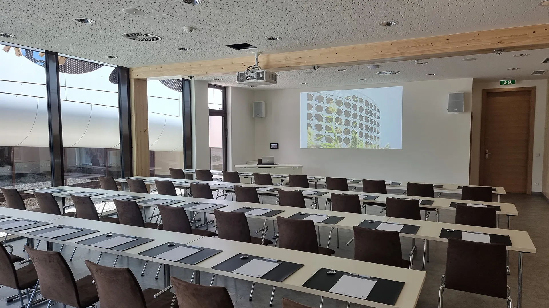Seminarraum mit Reihenbestuhlung, Tischen und Leinwand