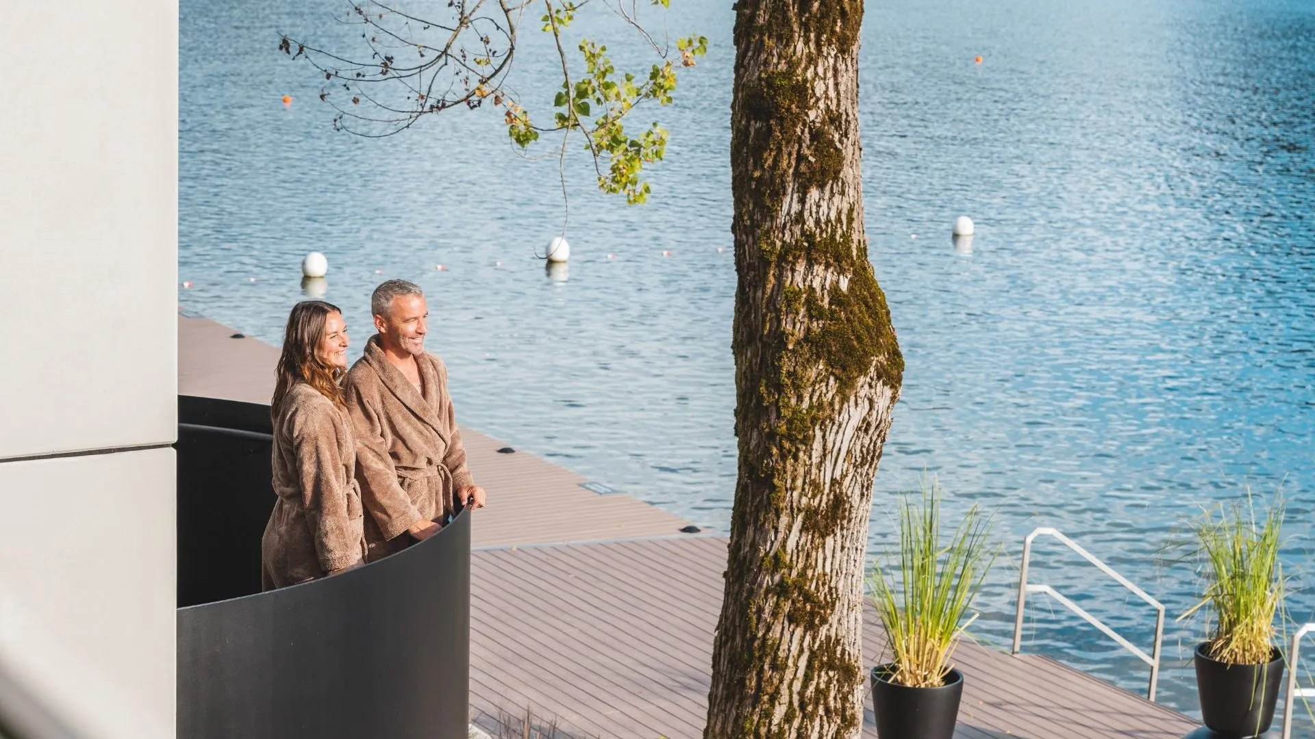Paar in Bademänteln auf Terrasse am See